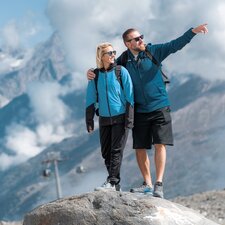 Couple standing on a rock, the MEX and the Zermatt mountains in the background | © basic_home