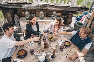 Deux couples trinquent avec un verre de vin rouge.  | © Gabriel Perren