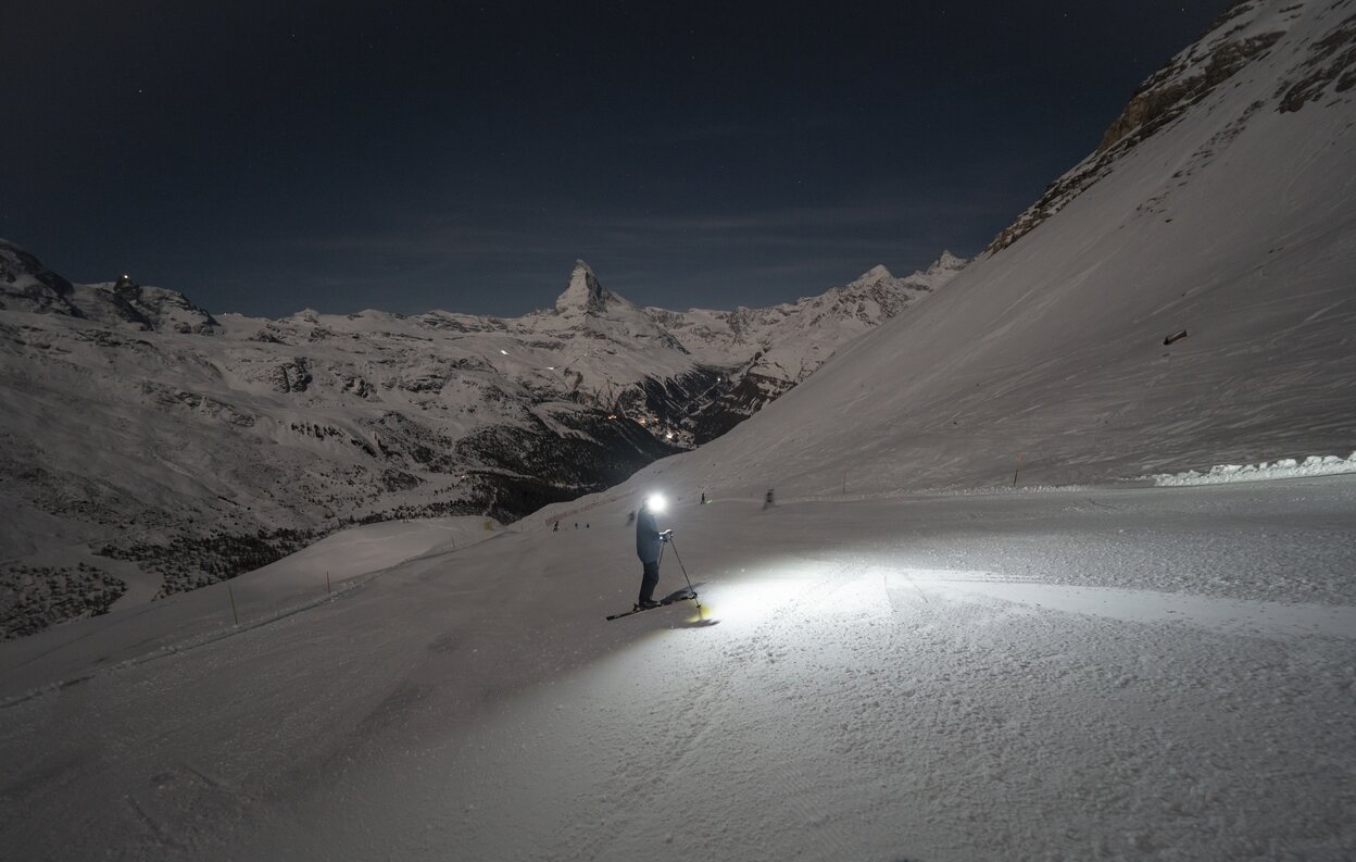 Skifahrer mit Stirnlampe auf dunkler Piste mit Matterhorn im Hintergrund | © Gabriel_Perren