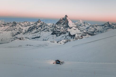 Pistenfahrzeug im Morgenrot in Mitten der Zermatter Gipfel | © Zermatt Bergbahnen