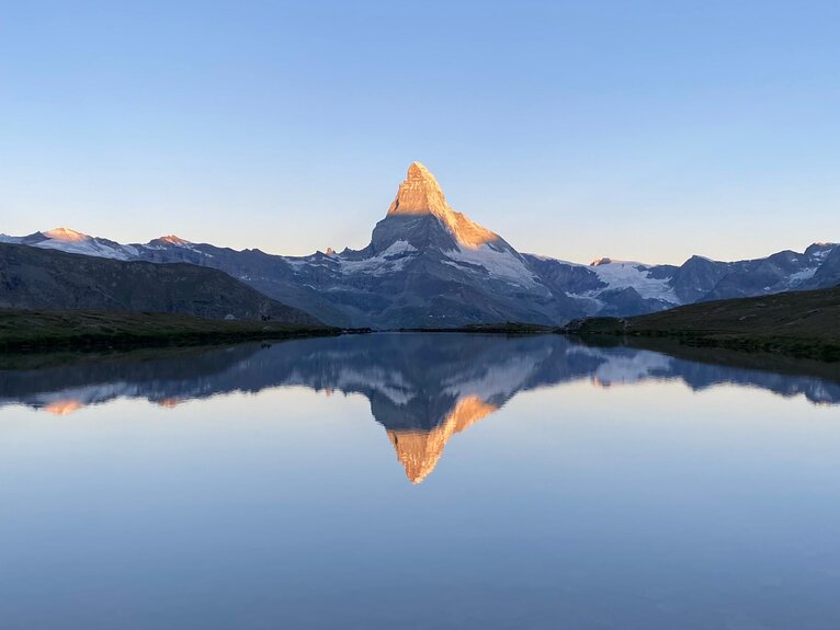 Lever de soleil classique avec le reflet du Cervin avec son sommet lumineux dans le lac clair de Stelli | © Zermatt Bergbahnen