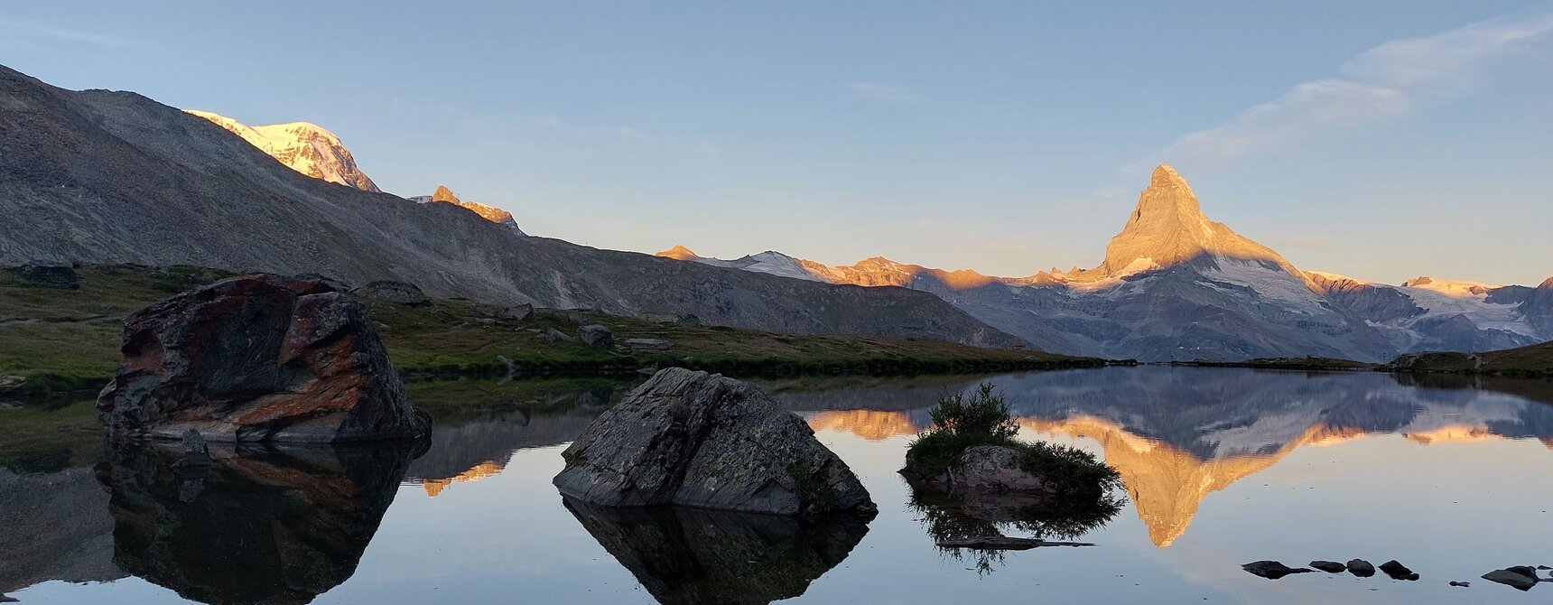 Le Cervin se reflète dans le lac Stelli. Les sommets qui entourent le Cervin sont également illuminés par les premiers rayons du soleil. | © Zermatt Bergbahnen
