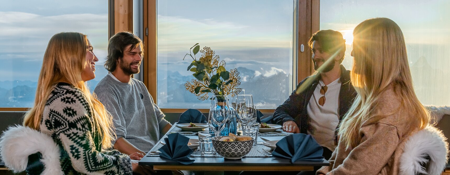 Due coppie sedute al tavolo del ristorante Glacier Paradise al tramonto | © basic home production