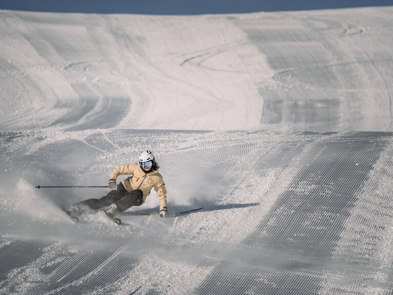 Skier making a left turn on freshly groomed slopes. | © Gabriel Perren