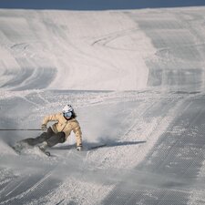 Skifahrerin macht eine Linkskurve auf frisch präparierten Pisten. | © Gabriel Perren