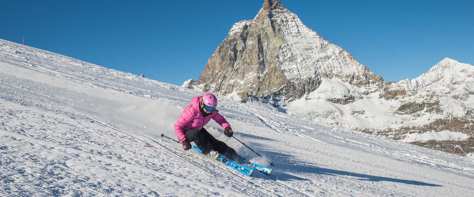 Skiing area south | © Michi Portmann Frau mit pinker Jacke fährt den Furggsattel hinunter, im Hintergrund das Matterhorn | © Michi Portmann