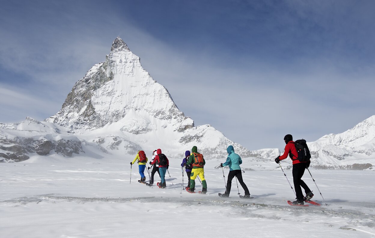 Eine Gruppe von Schneeschuhläufer unterwegs auf dem Trail, im Hintergrund das Matterhorn | © Michi_Portmann