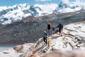 Family hiking down rocks, in the background, Breithorn and Dufourspitze | © basic_home