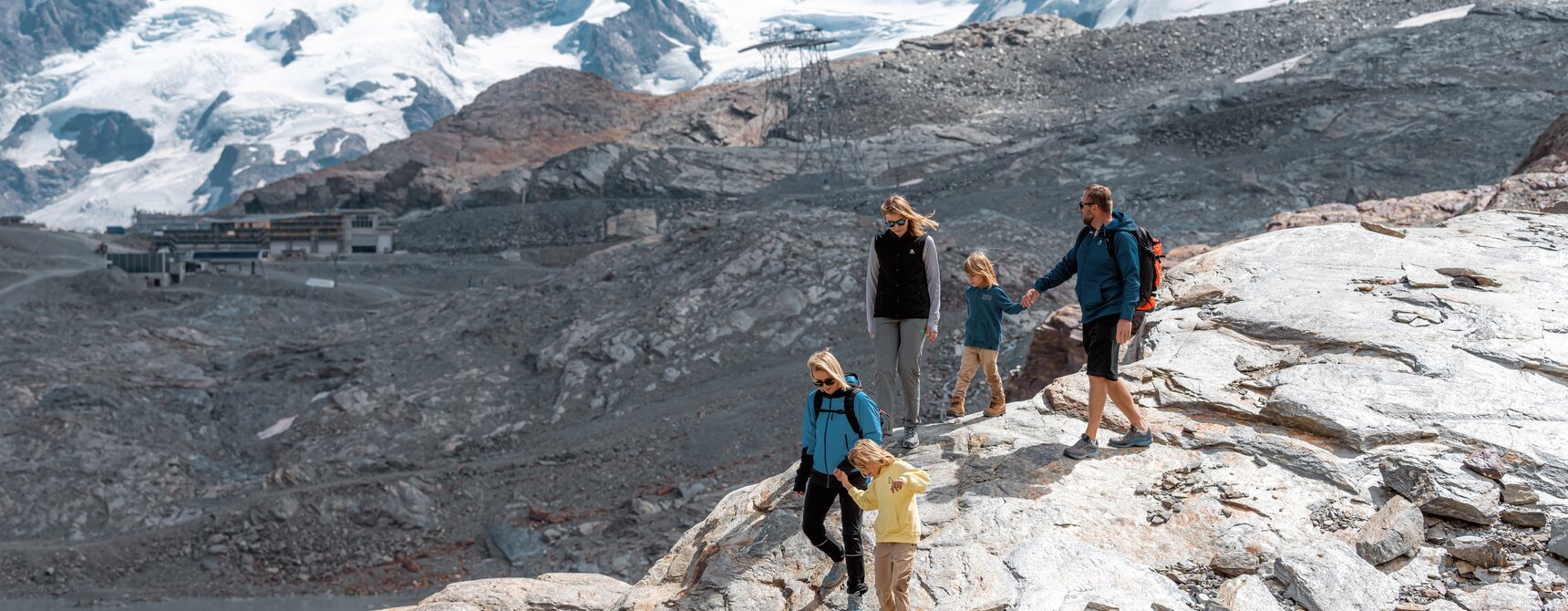 Family hiking down rocks, in the background, Breithorn and Dufourspitze | © basic_home