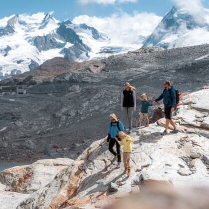 Familie wandert Felsen hinunter, im Hintergrund, Breithorn und Dufourspitze | © basic_home