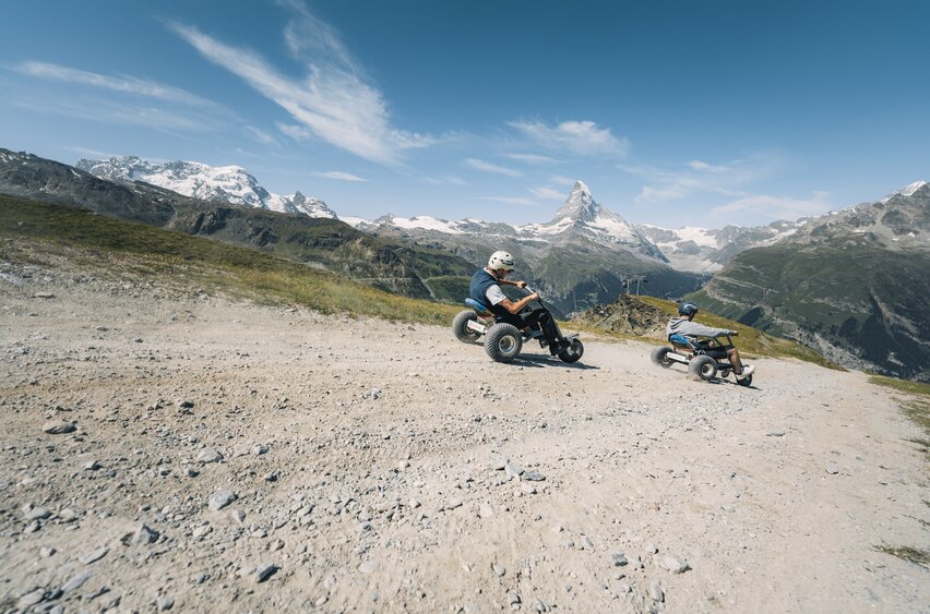 Zwei Männer preschen mit den Mountaincarts den Weg hinunter mit dem Matterhorn im Hintergrund. | © Gabriel Perren