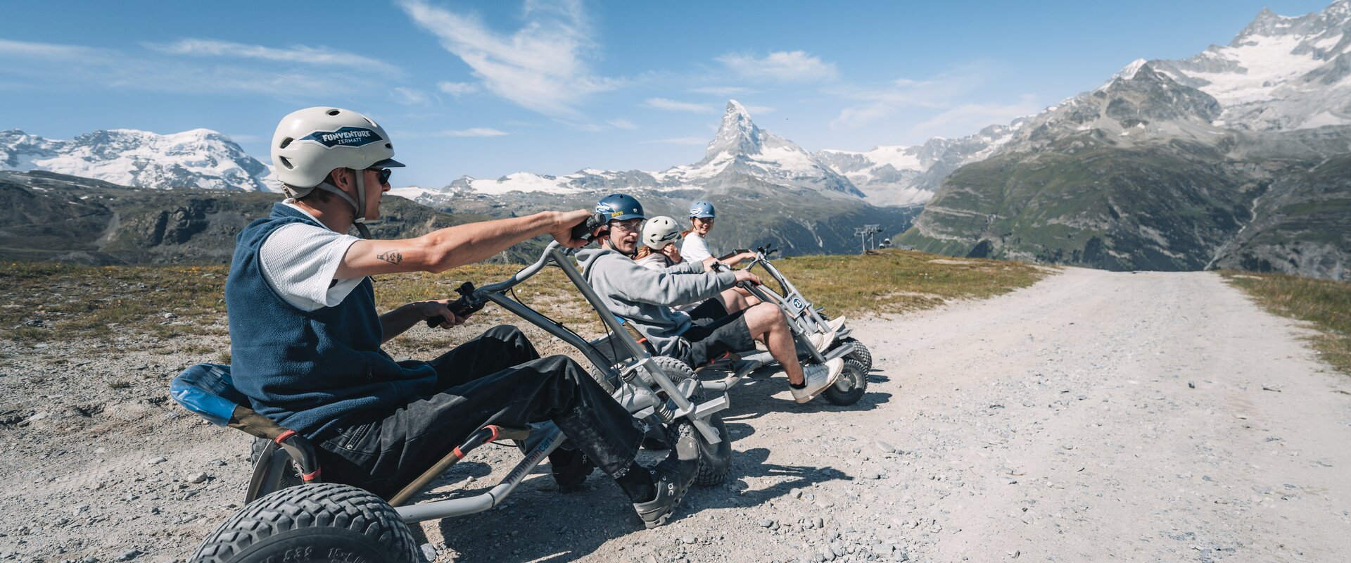 Un groupe est assis dans son mountaincarts, prêt à partir, par un temps idéal et avec une vue sur le Cervin.  | © Gabriel Perren