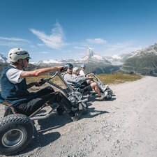 Un gruppo si siede pronto a partire con i loro mountaincarts con il tempo migliore e la vista del Cervino.  | © Gabriel Perren